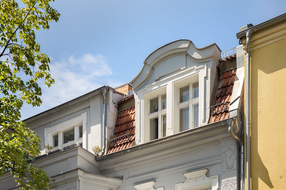 Fassade eines Wohnhauses mit Gaube und weißem Fenster unter blauem Himmel.