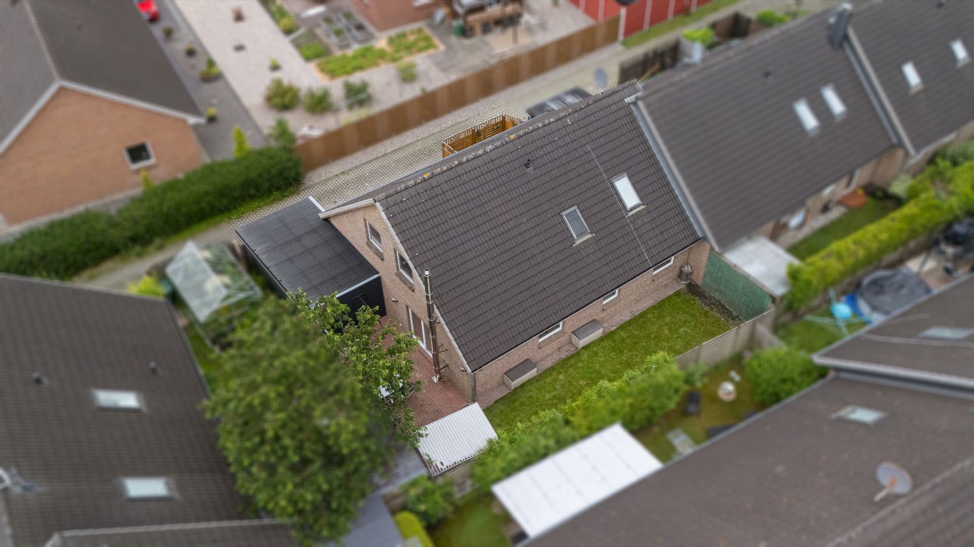 Luftaufnahme eines Reihenhauses mit Garten, umgeben von weiteren Häusern.