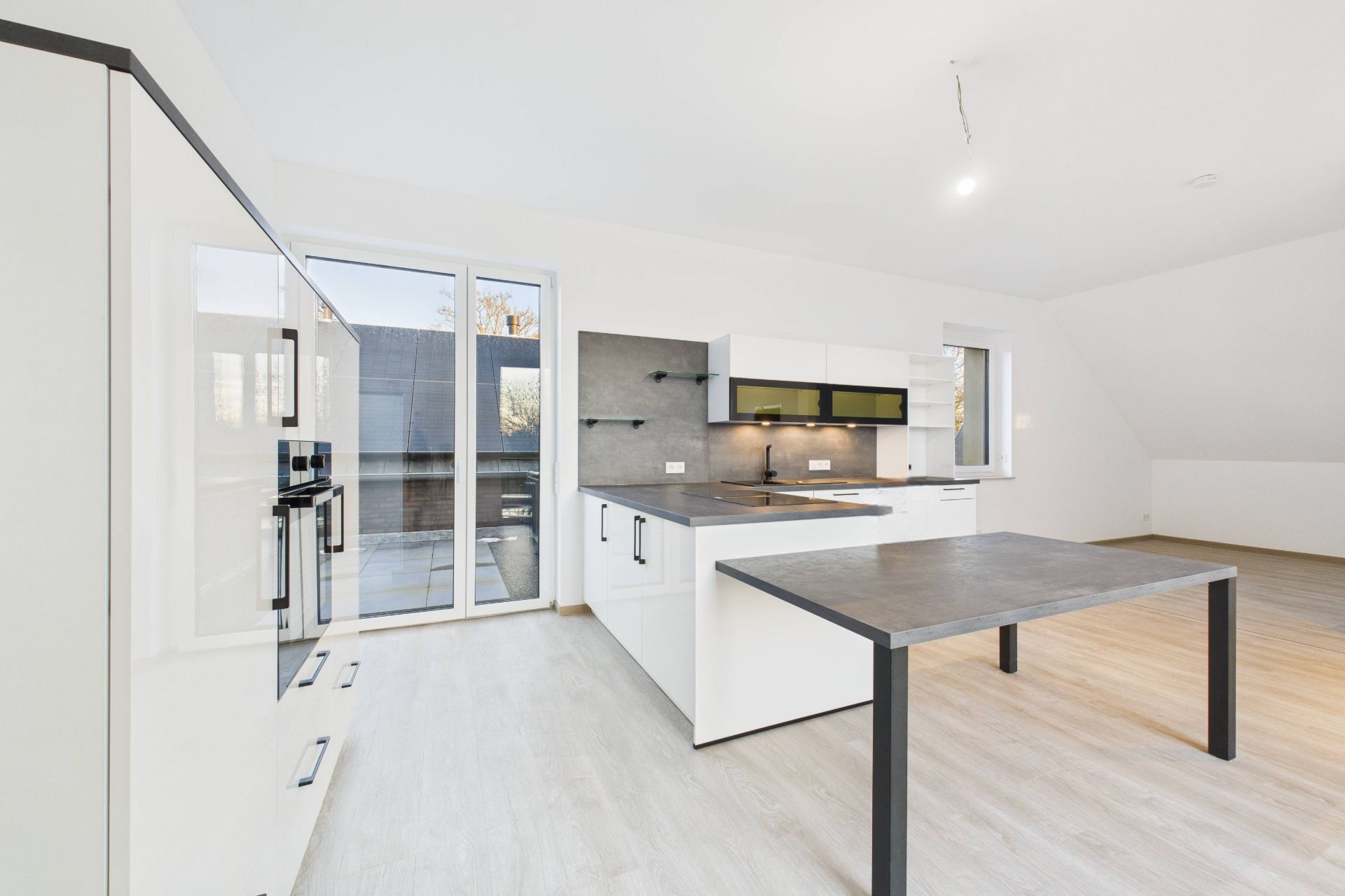 Moderne helle Küche mit Einbauschränken, Kochinsel und großem Fenster zum Balkon.