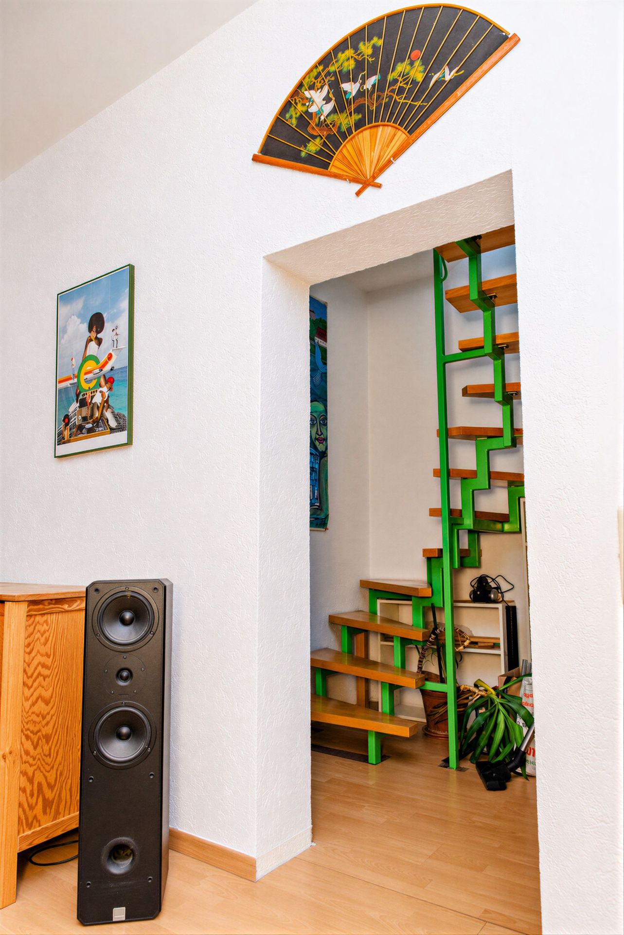 Innenraum mit Lautsprecher, Holzschrank, farbiger Treppe und Deko-Fächer an der Wand.