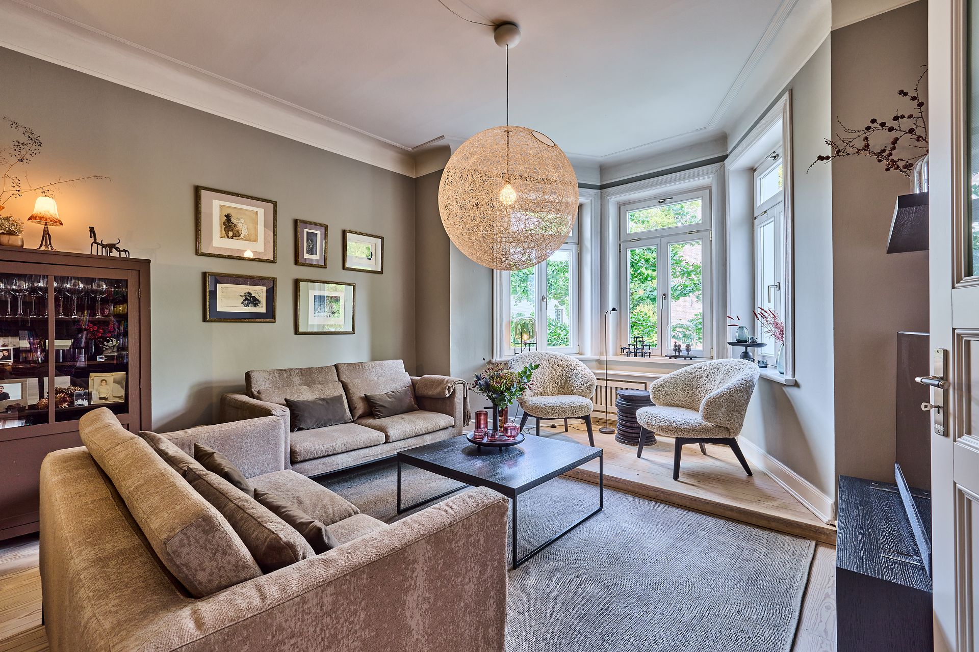 Helles Wohnzimmer mit zwei Sofas, zwei Sesseln, Couchtisch und großen Fenstern.
