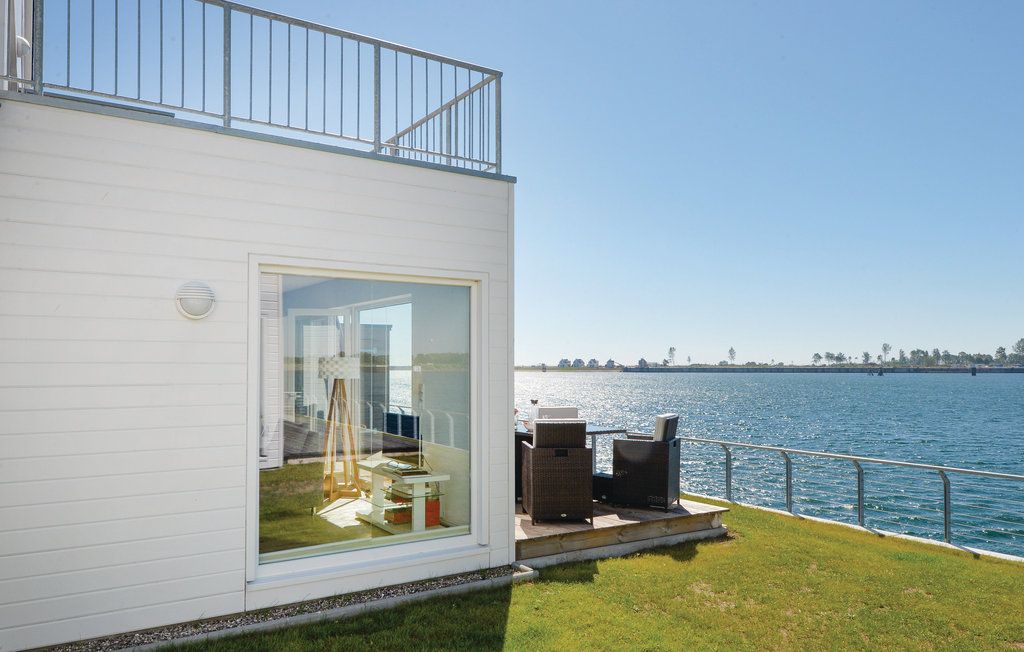 Eckansicht eines weißen Hauses am Wasser mit Terrasse und Rasenfläche.