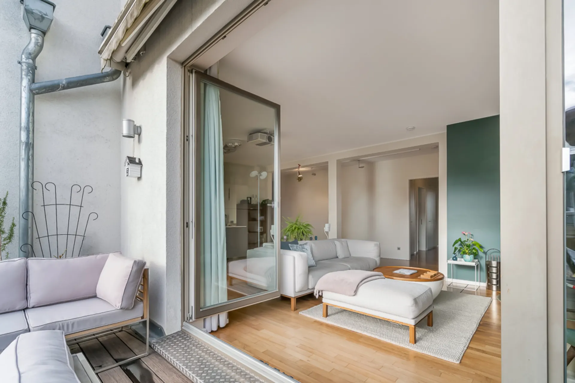 Offener Wohnbereich mit Sofa und Couchtisch, angrenzend an eine Terrasse mit Sitzmöbeln.