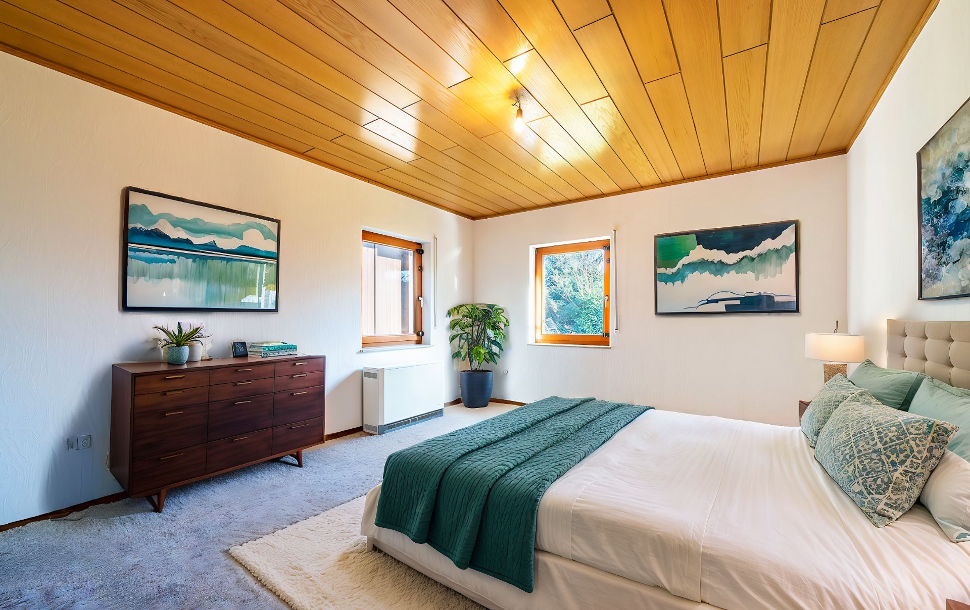 Helles Schlafzimmer mit Holzbett, Kommode, Pflanze und moderner Wandkunst.