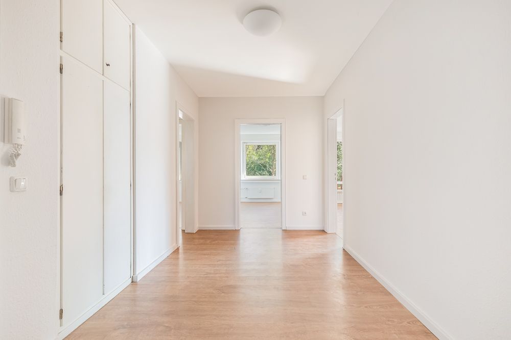 Heller Flur mit Holzfußboden, weißen Wänden und Einbauschrank in einer Wohnung.