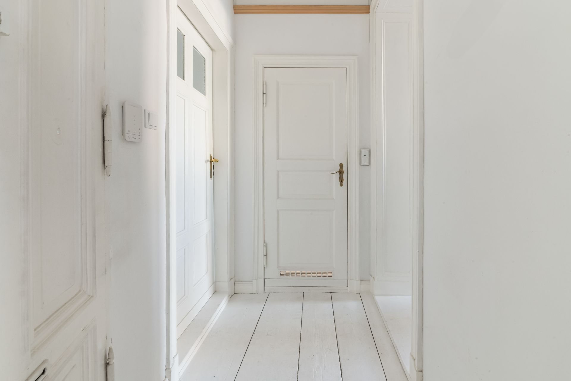 Heller Flur mit weißen Holztüren und weißem Holzboden in einer Wohnung.