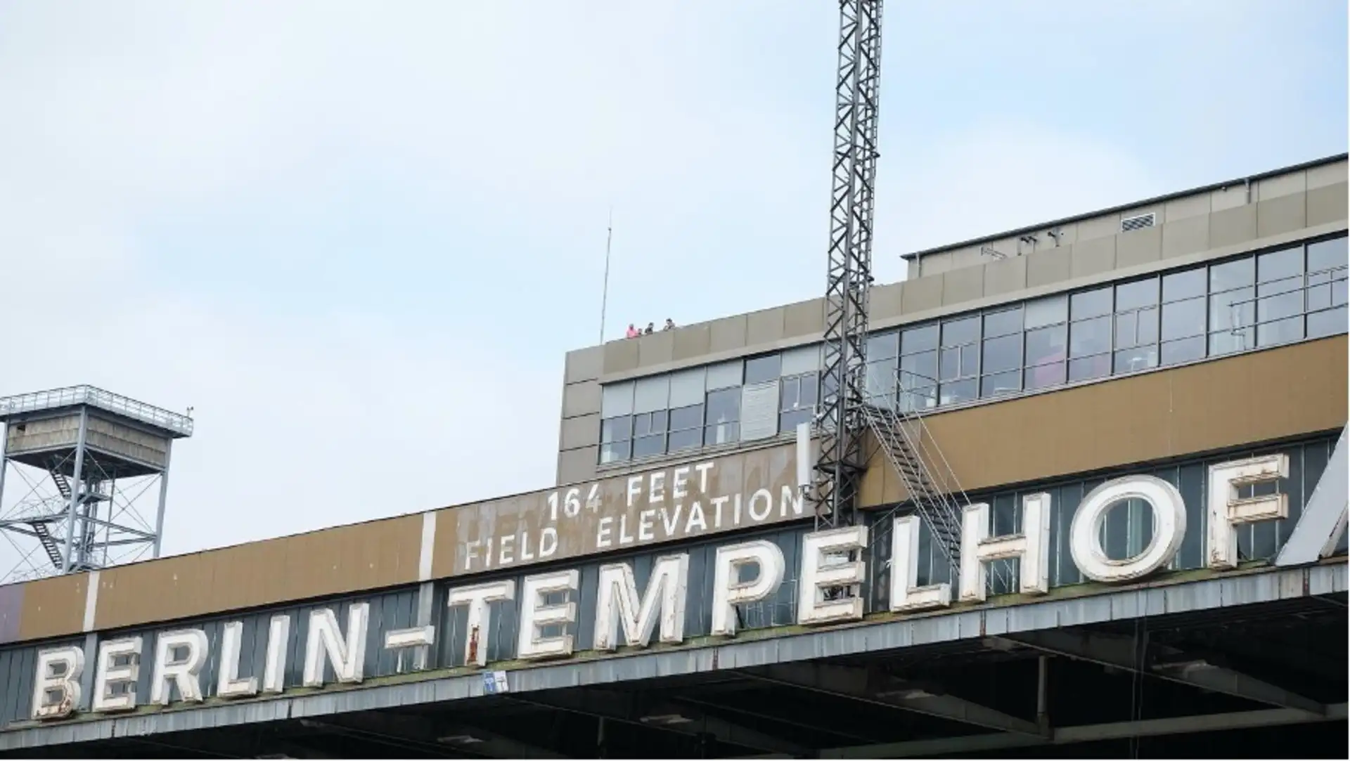 Gebäude mit großem Schild 'BERLIN-TEMPELHOF' und weiteren Schildern darüber.