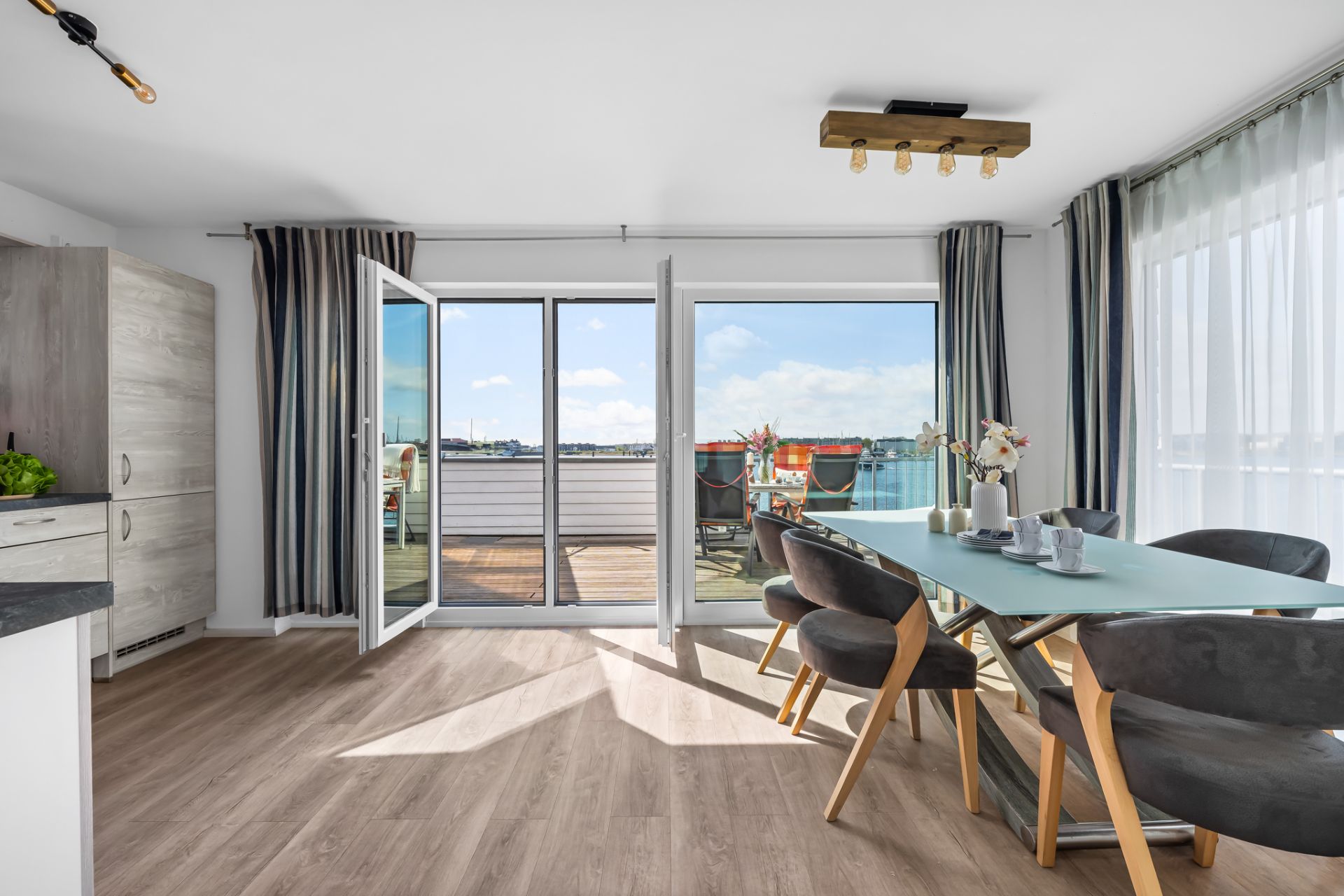 Helles Esszimmer mit großem Tisch, sechs Stühlen und Zugang zu einer möblierten Terrasse.