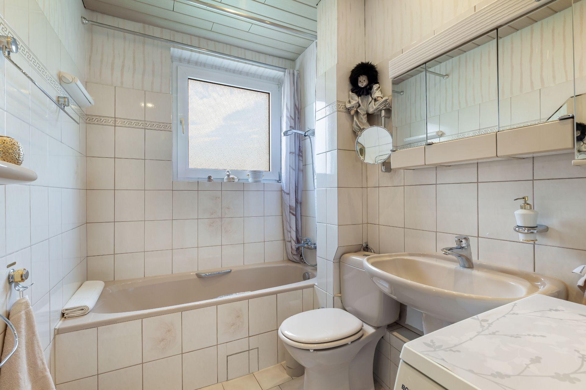 Helles Badezimmer mit Badewanne, WC, Waschbecken und Spiegel über dem Waschbecken.
