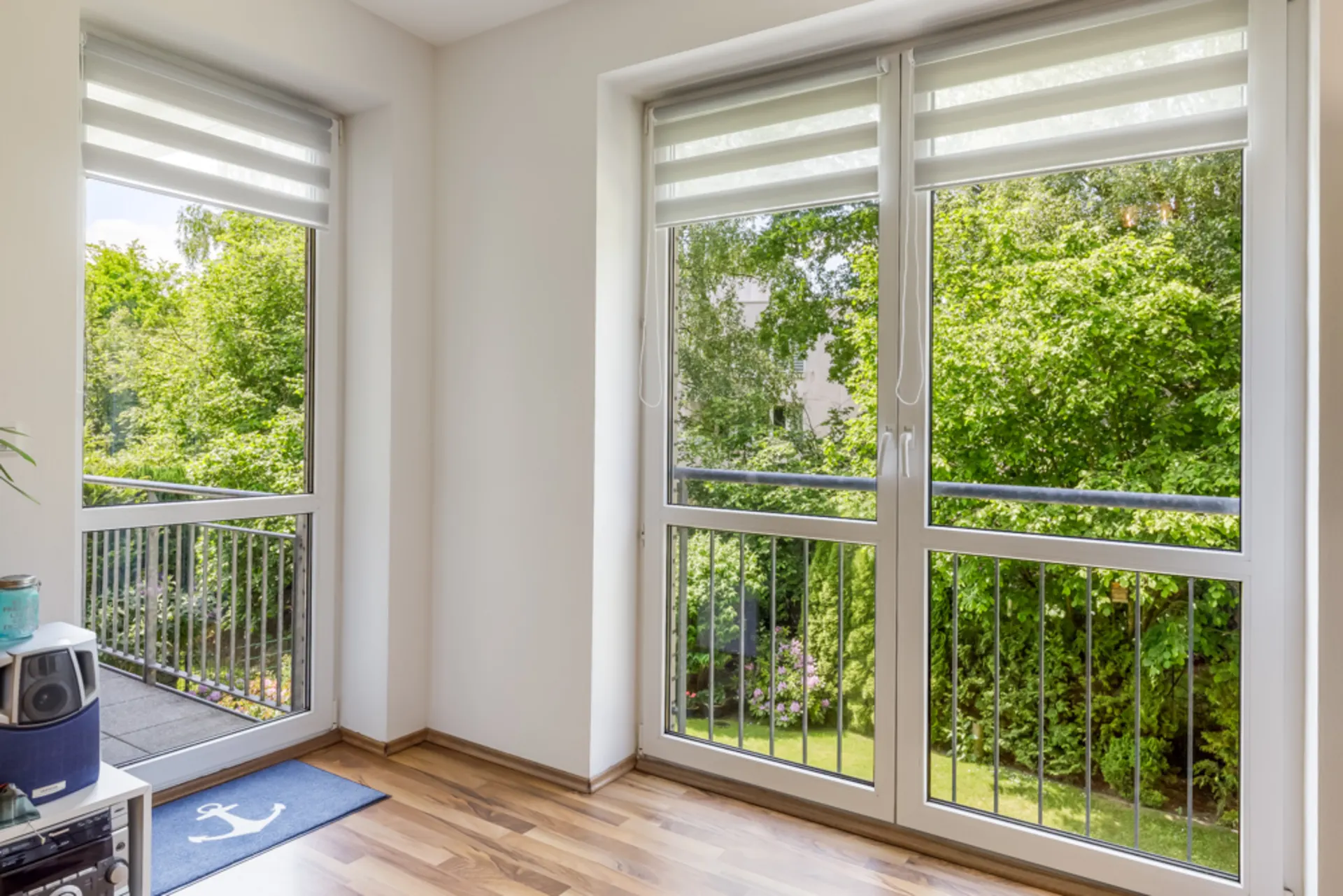 Helle Ecke mit zwei großen Fenstern und Blick auf einen grünen Garten.