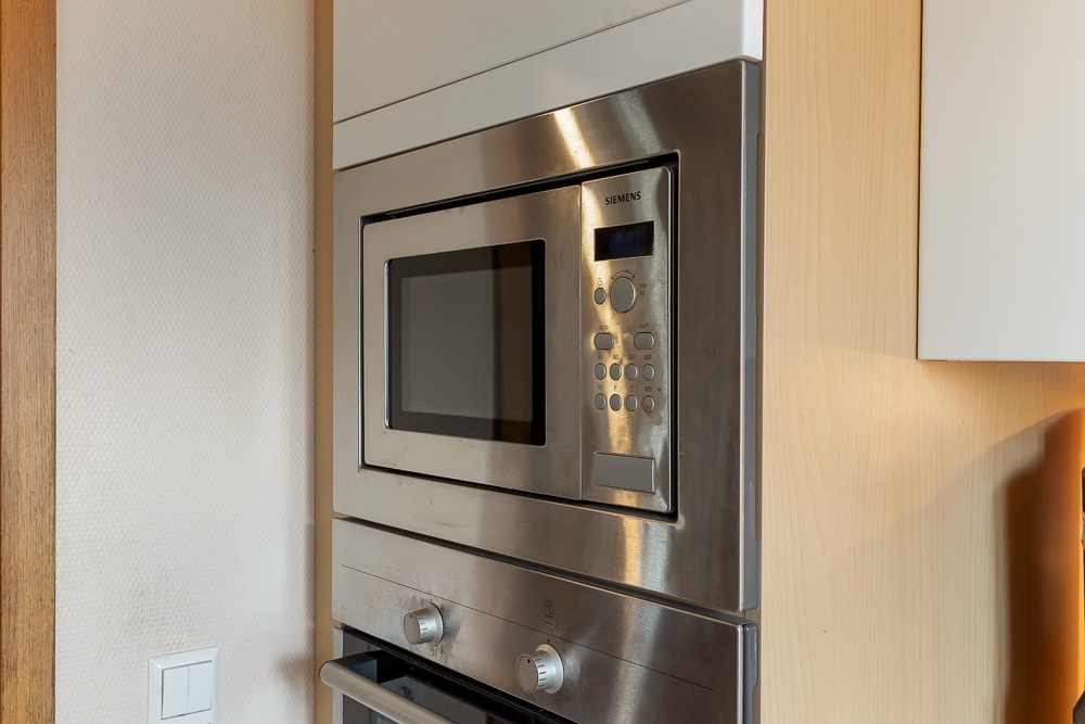 In eine Küchenwand eingebaute Mikrowelle und Backofen aus Edelstahl.