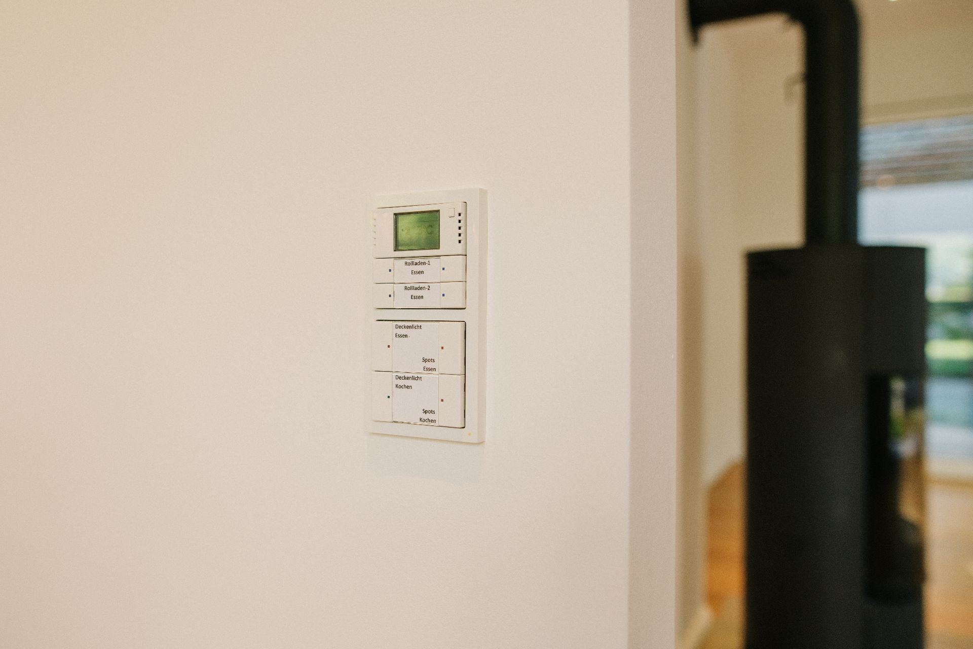 Eine Steuerungseinheit mit Display ist an einer weißen Wand montiert.