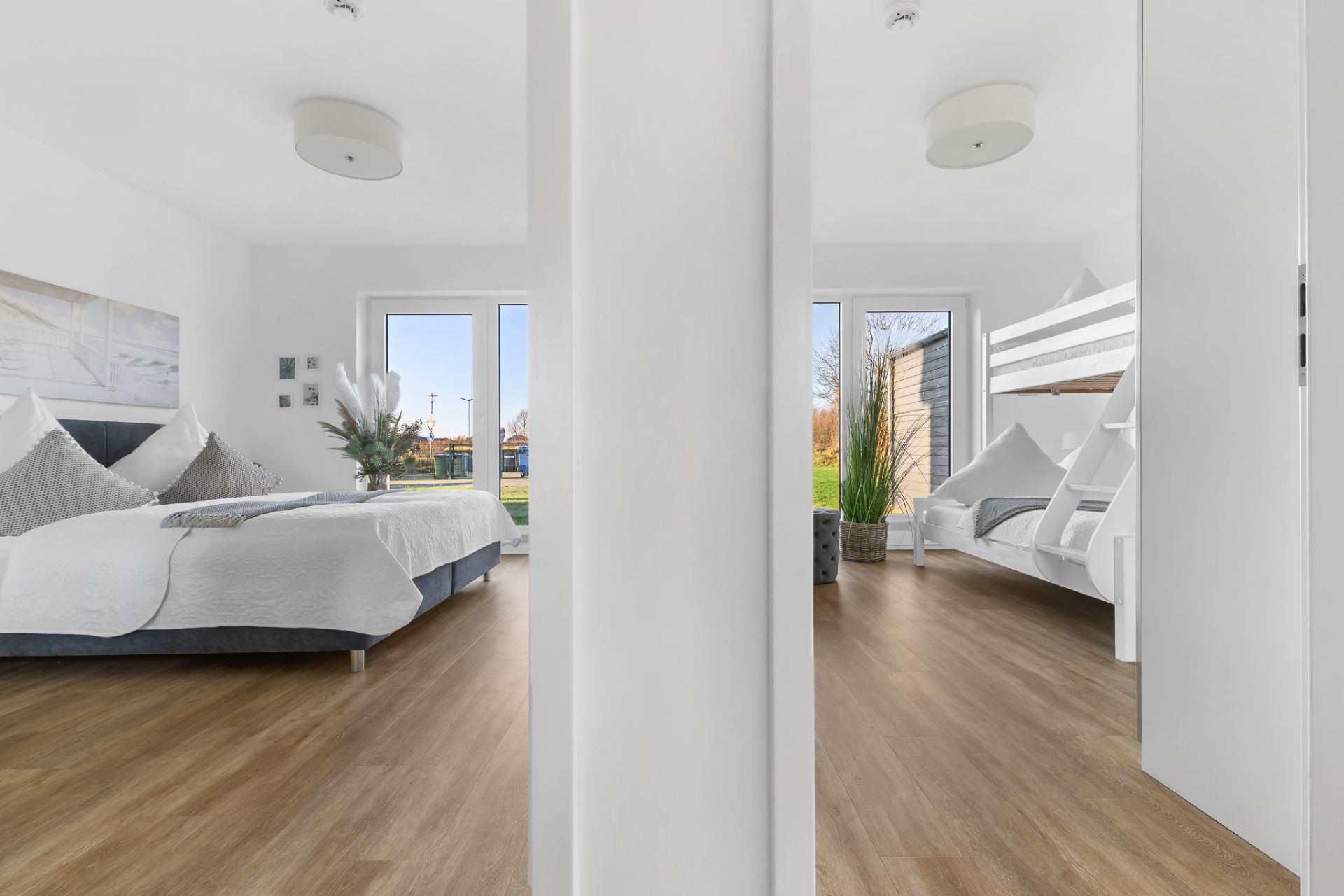 Zwei helle Zimmer mit Holzboden, links ein Doppelbett, rechts ein Etagenbett und Sessel.