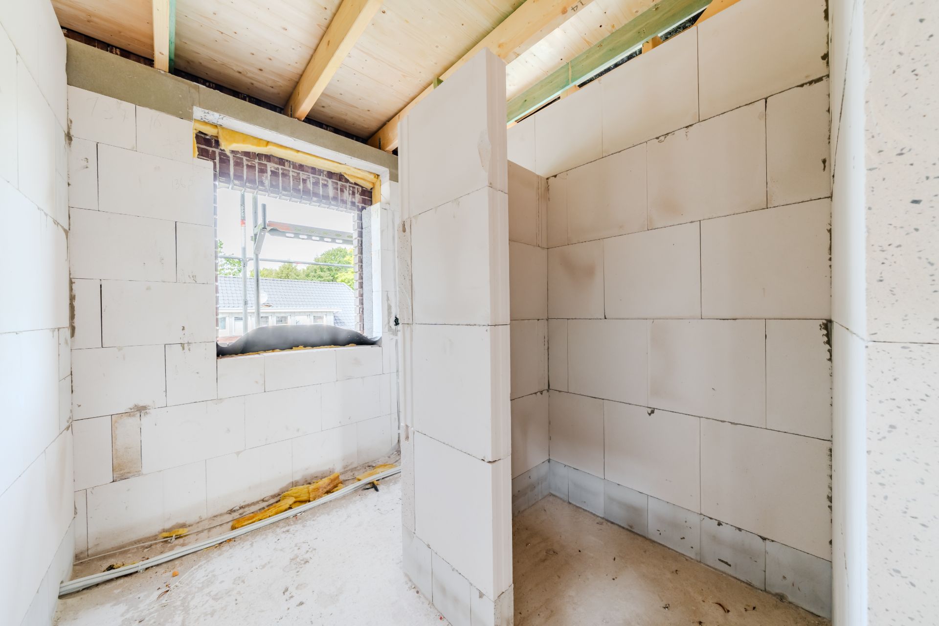 Rohbau eines kleinen Raumes mit offenen Wänden und Fenster, Innenansicht.