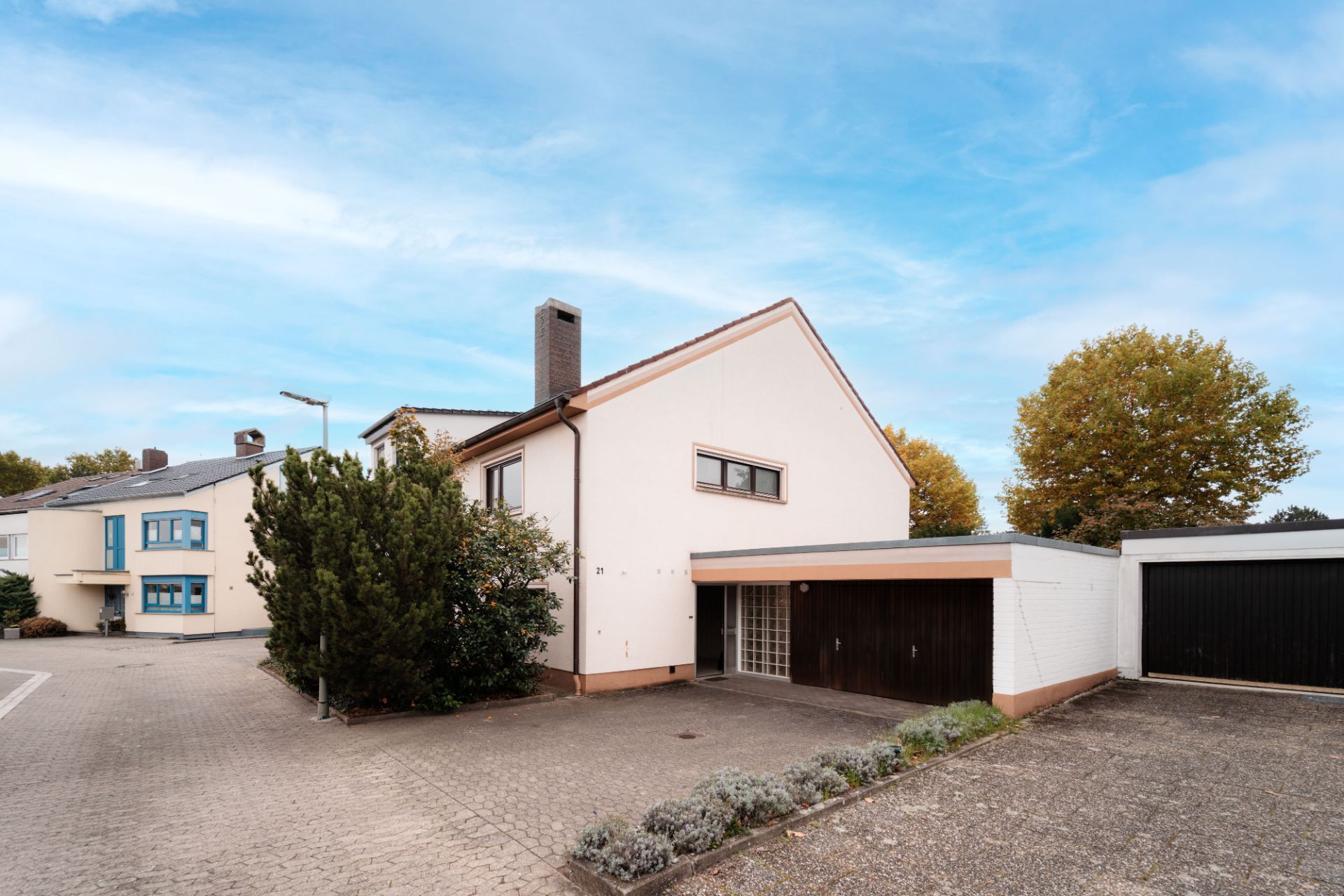 Zweistöckiges Wohnhaus mit Garage, Einfahrt und kleinen Sträuchern vor dem Haus.