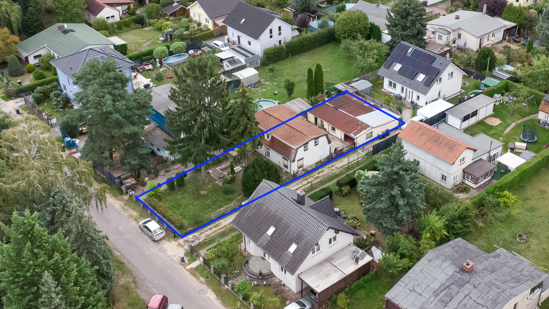 Luftaufnahme eines Grundstücks mit zwei Gebäuden und Garten, durch eine blaue Linie markiert.