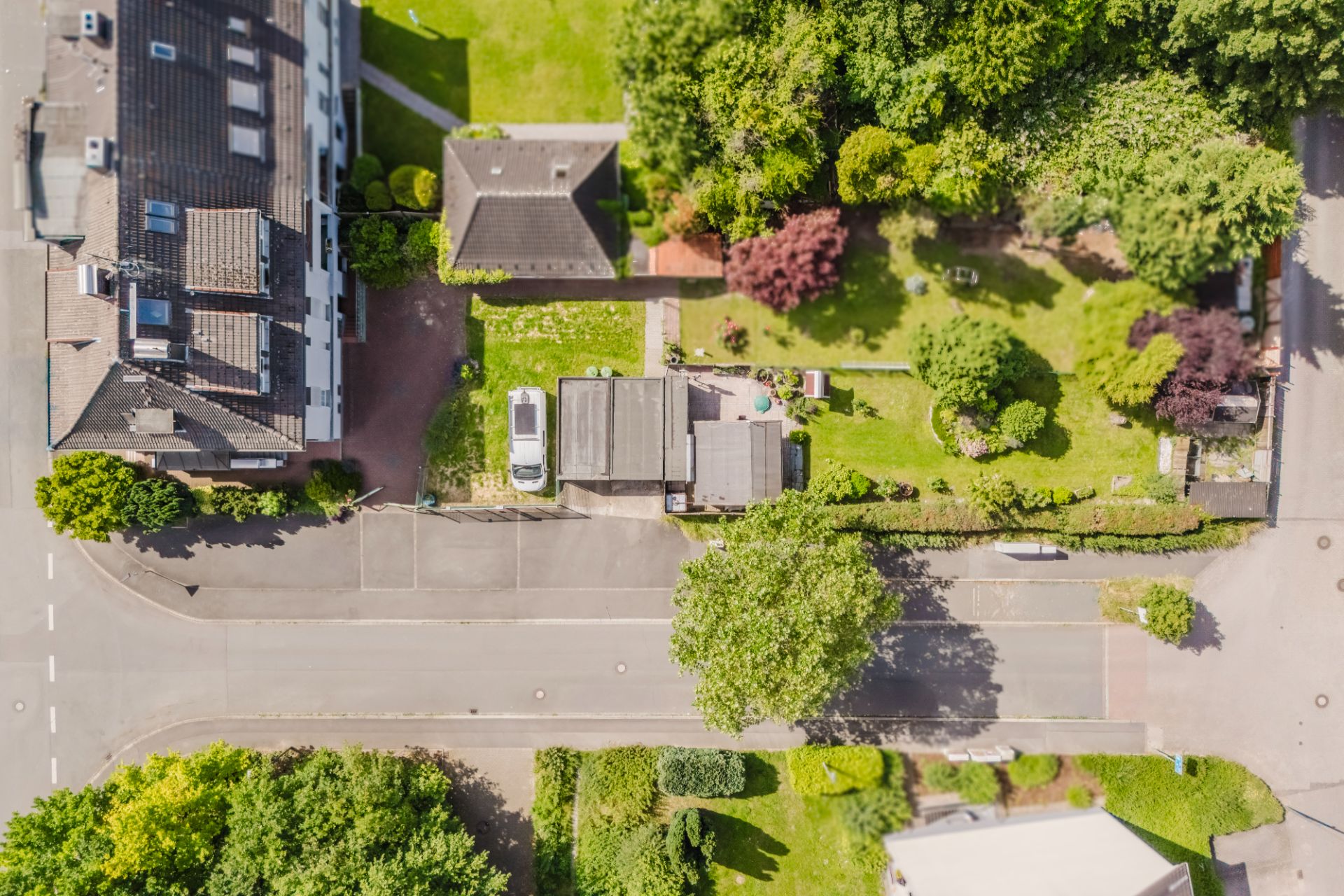 Luftaufnahme eines Wohnhauses mit Garten, Auto und umliegenden Straßen.