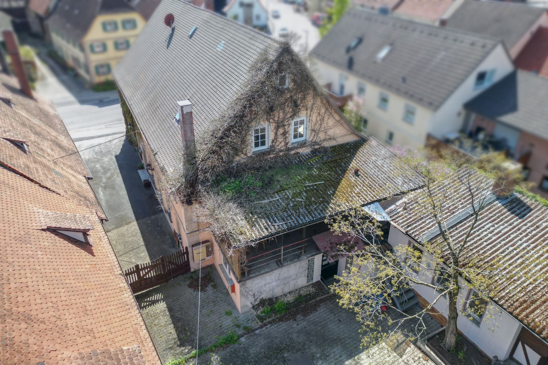 Luftaufnahme eines Wohnhauses mit begrüntem Dach und Innenhof, umgeben von weiteren Häusern.