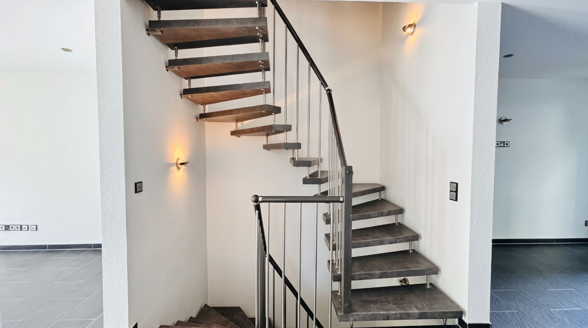 Moderne gewendelte Treppe mit Metallgeländer in einem hellen Wohnraum.