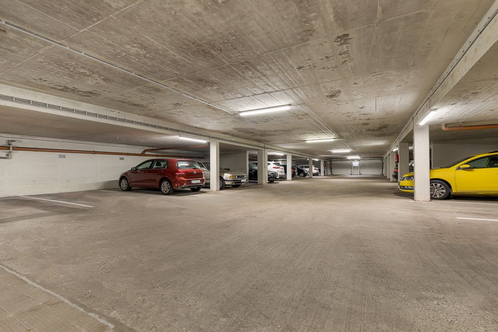 Tiefgarage mit mehreren geparkten Autos und beleuchtetem Betonboden.