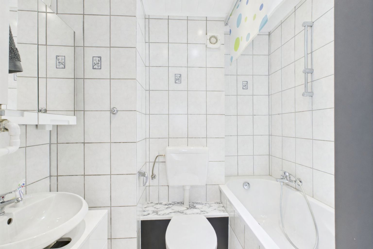 Helles Badezimmer mit Badewanne, WC, Waschbecken und weißen Fliesen.