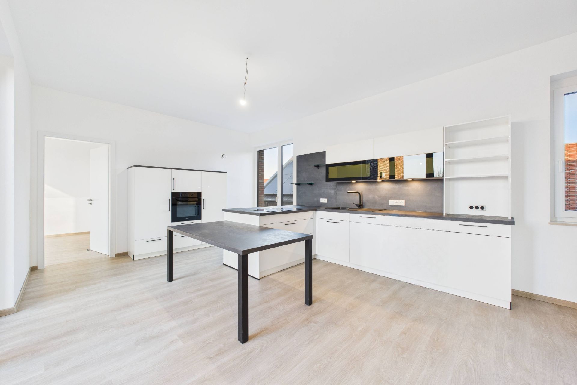 Helle, moderne Einbauküche mit weißen Schränken und Esstisch auf Holzfußboden.
