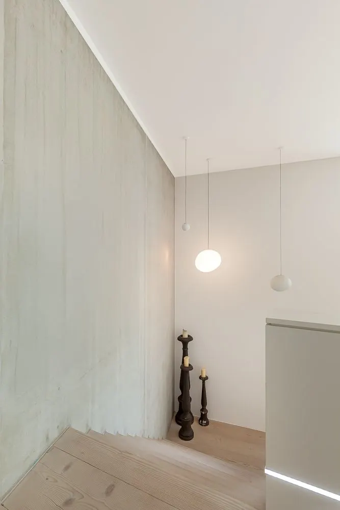 Treppenaufgang mit Holzstufen, drei Kerzenständern und modernen Hängelampen.