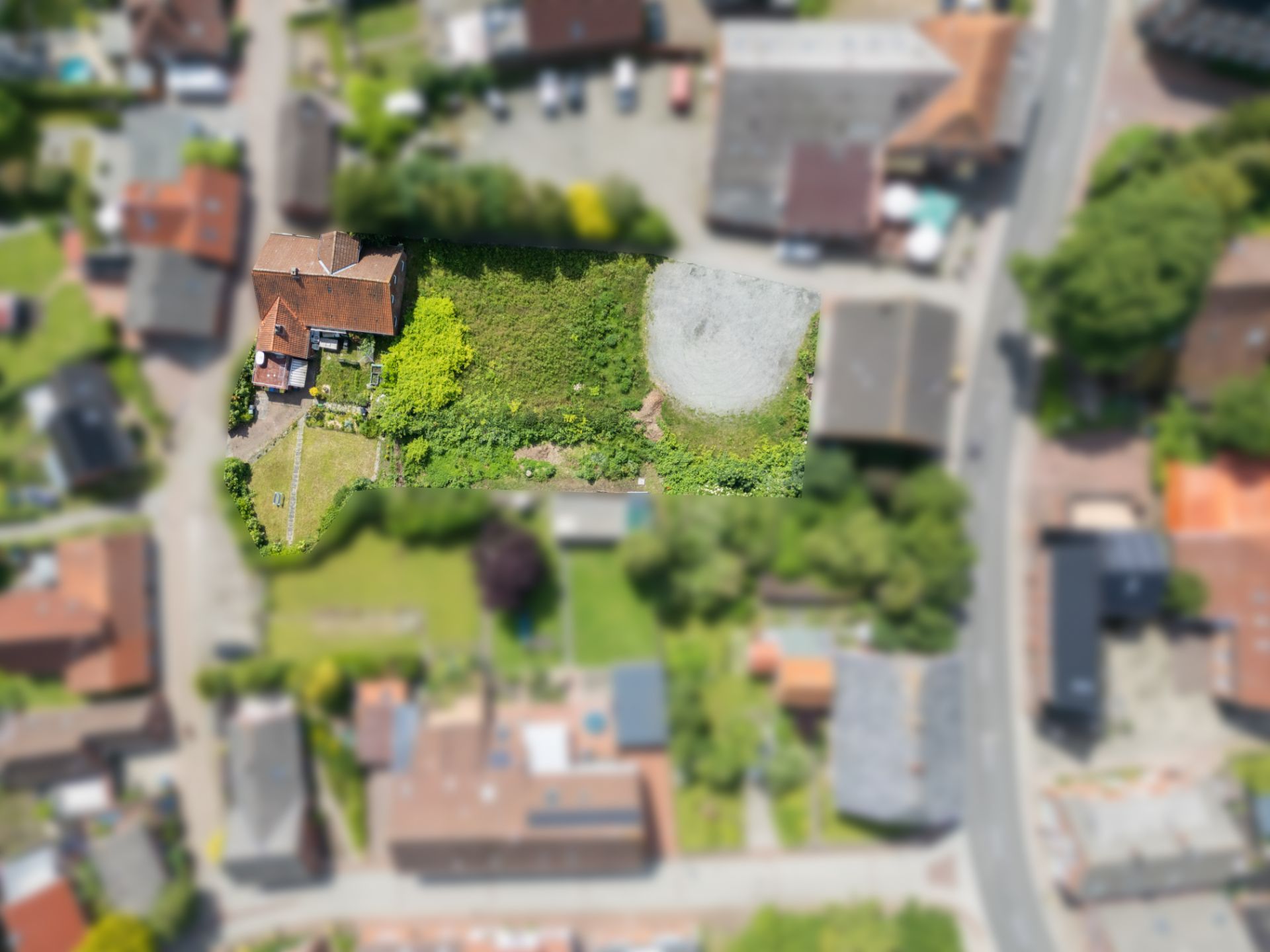 Luftaufnahme eines Hauses mit großem Garten und einer runden Fläche im Wohngebiet.