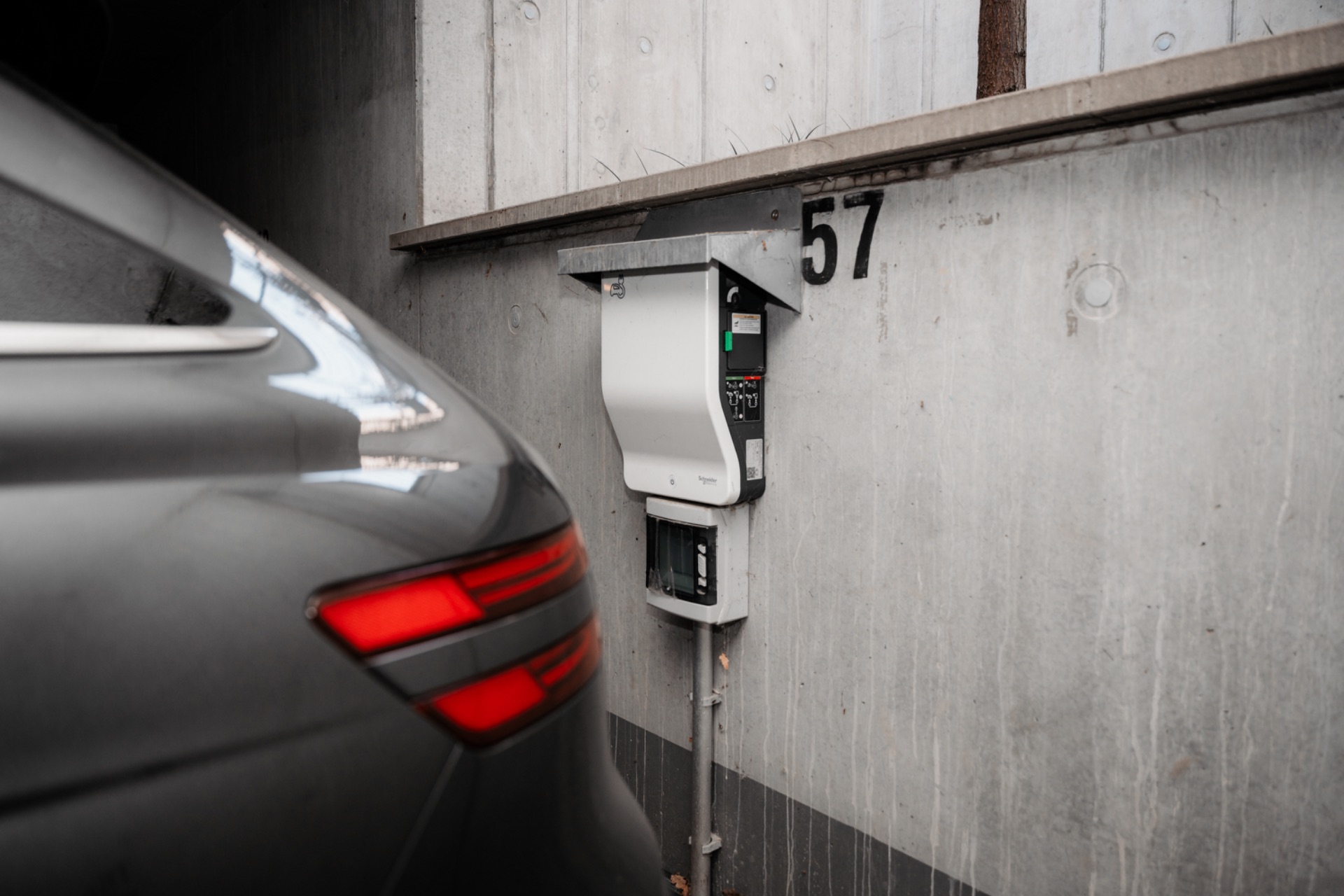Auto neben einer Ladestation an einer Betonwand mit der Nummer 57.