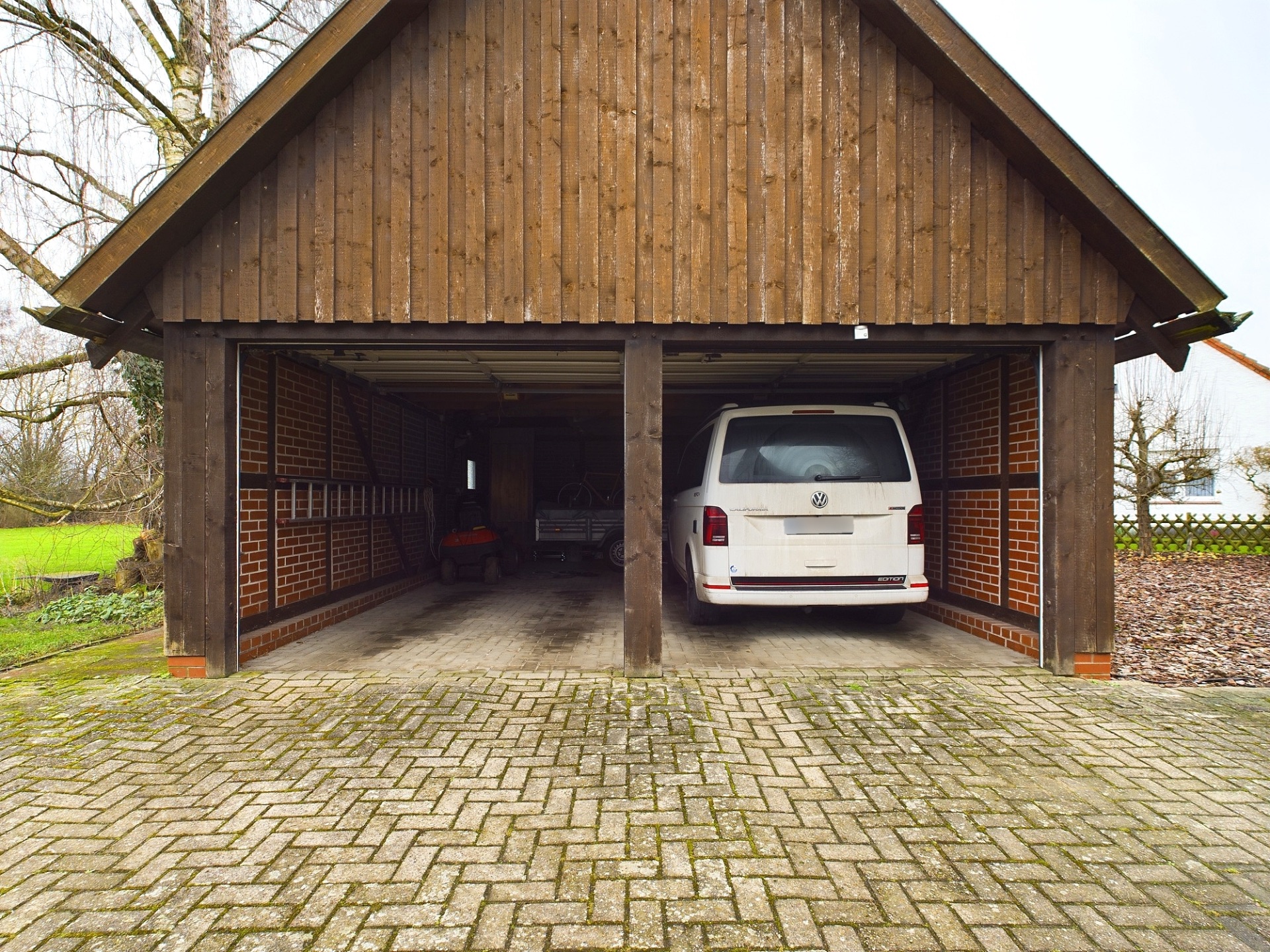 Offene Doppelgarage mit Holzverkleidung, ein weißes Auto steht auf der rechten Seite.