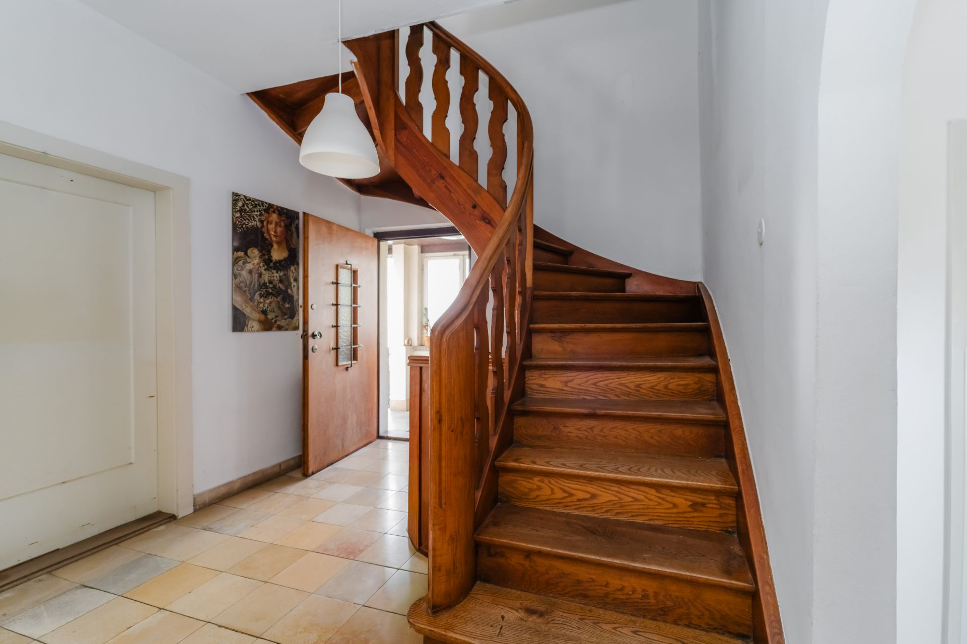 Holztreppe in einem Flur mit Fliesenboden und offener Eingangstür.