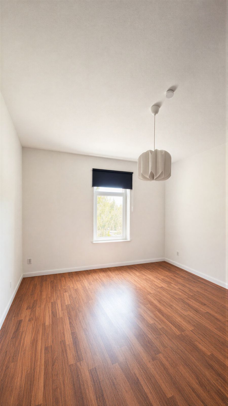 Leeres Zimmer mit Holzfußboden, weißer Wand, Fenster und moderner Deckenlampe.