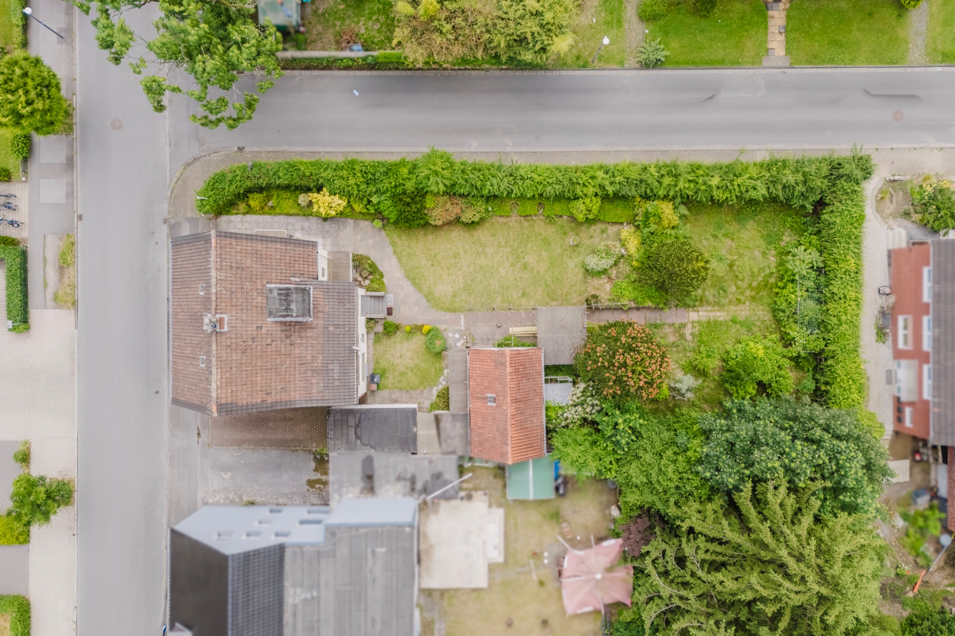 Luftaufnahme eines Wohnhauses mit Garten, Wegen und umliegenden Straßen.