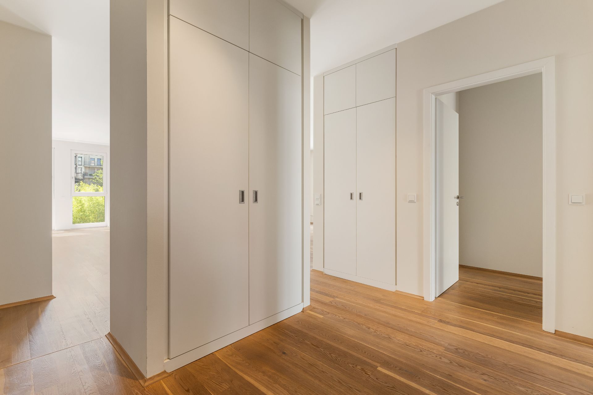 Heller Flur mit Einbauschränken und Holzboden, Türen führen in weitere Räume.