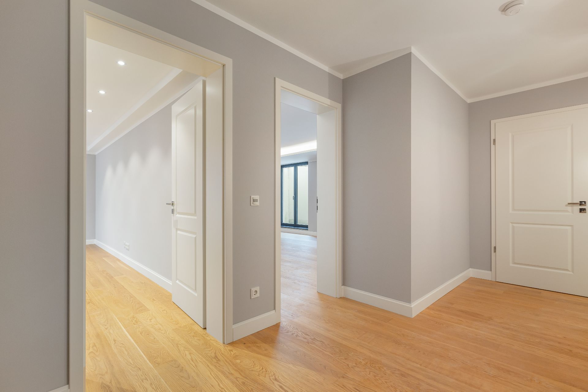Heller Flur mit Holzboden und mehreren weißen Türen in einer Wohnung.