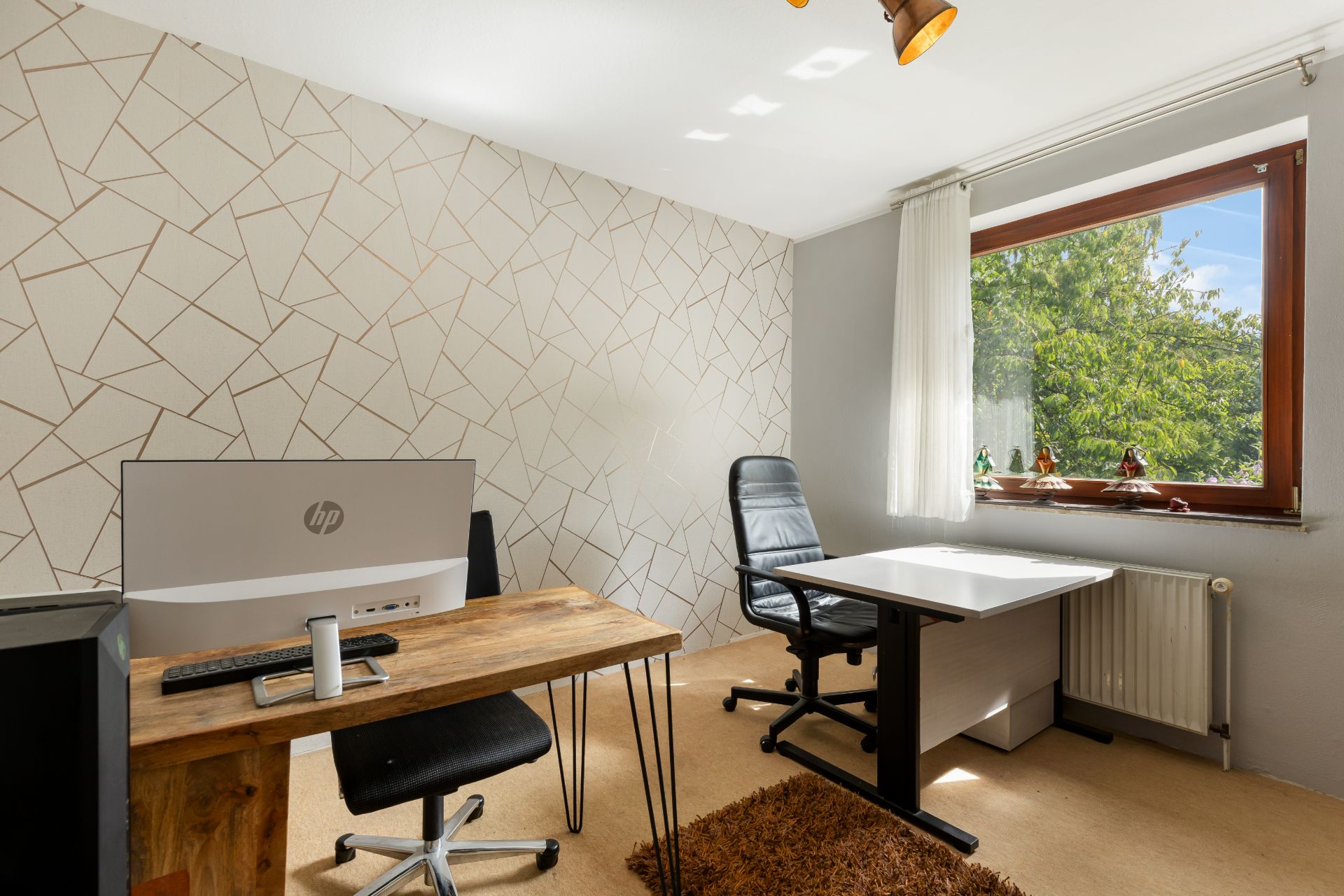 Helles Arbeitszimmer mit zwei Schreibtischen, Stühlen, großem Fenster und gemusterter Wand.
