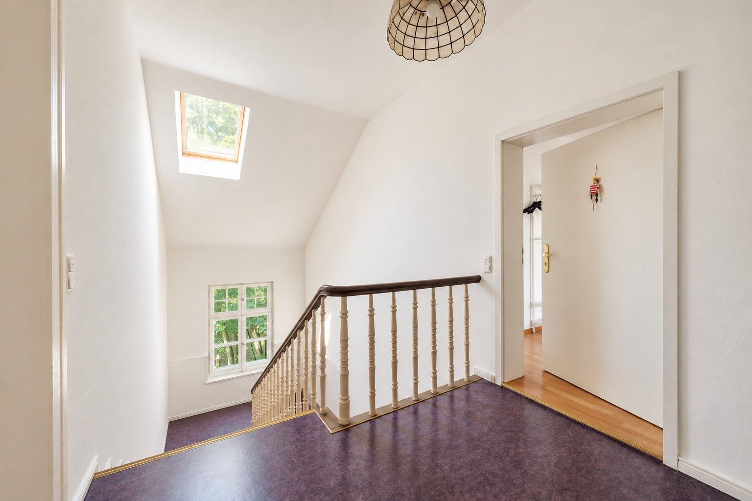 Heller Flur mit Treppe, Fenster und Dachfenster in einem Wohnhaus.