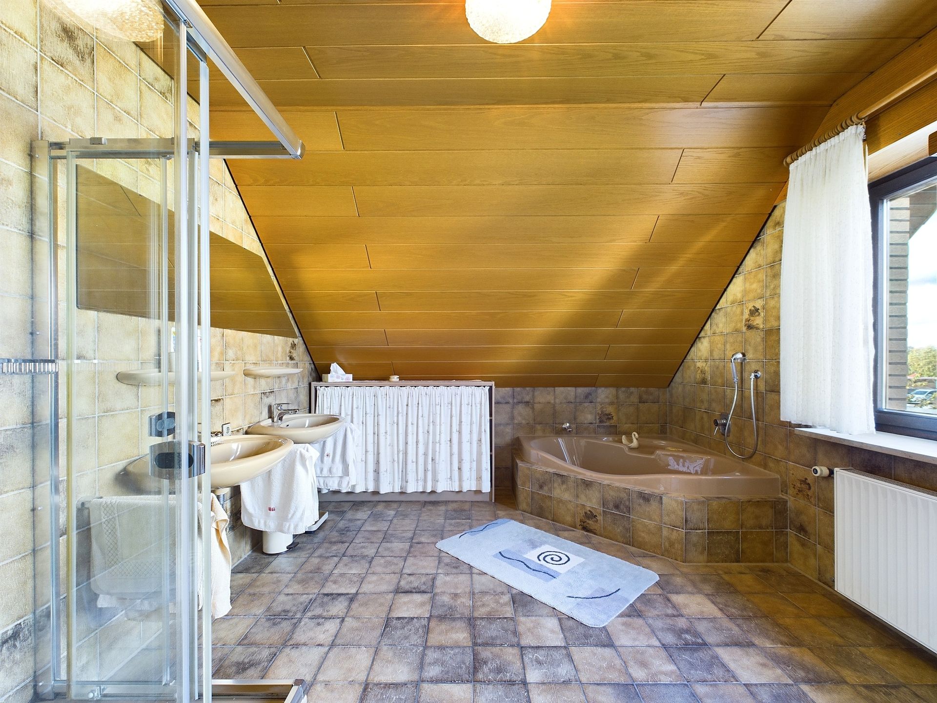Großes Badezimmer mit Dachschräge, Badewanne, Dusche, zwei Waschbecken und Fenster.