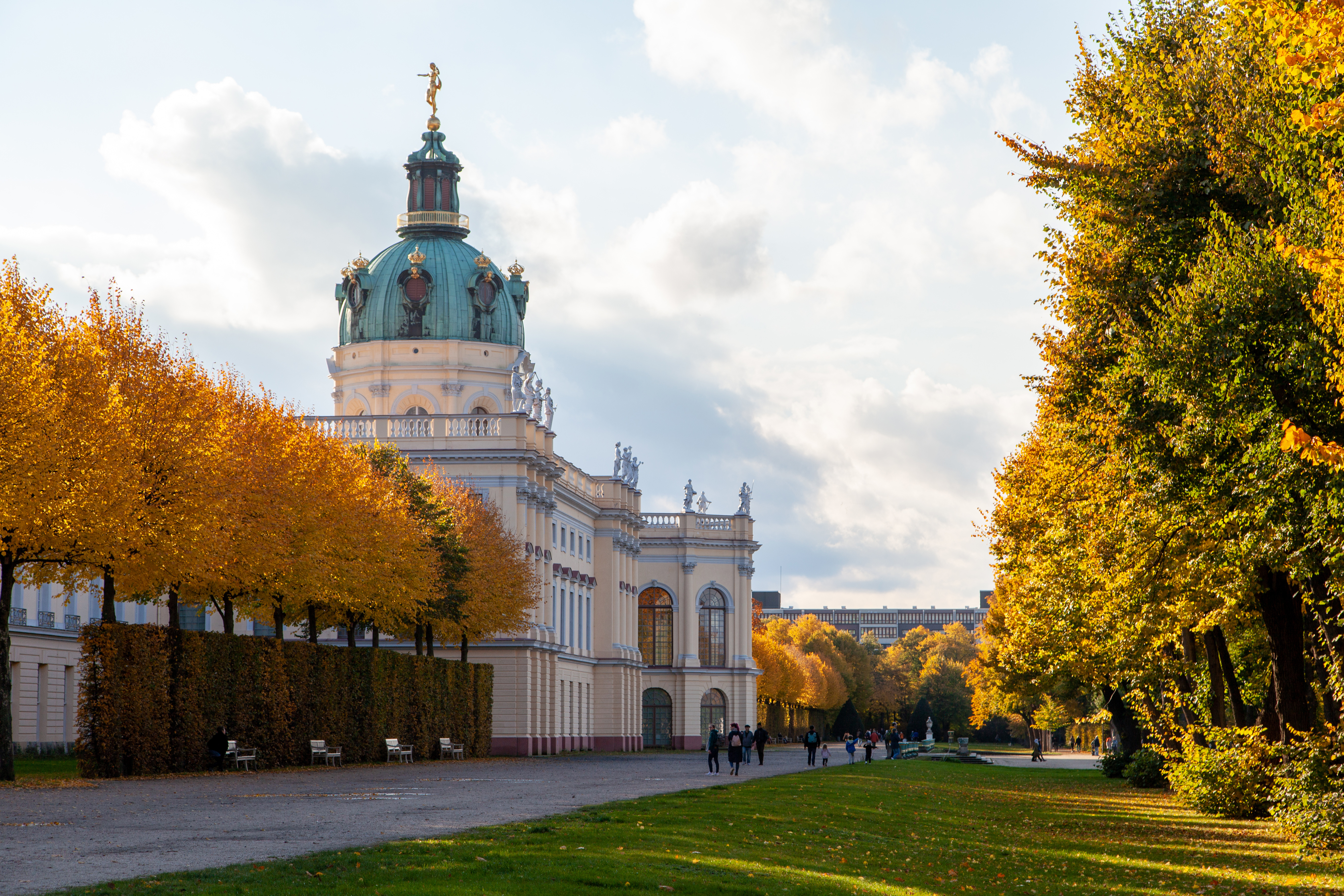 Stadtansicht mit modernen Hochhäusern und einer historischen Kirche im Vordergrund bei Sonnenuntergang.