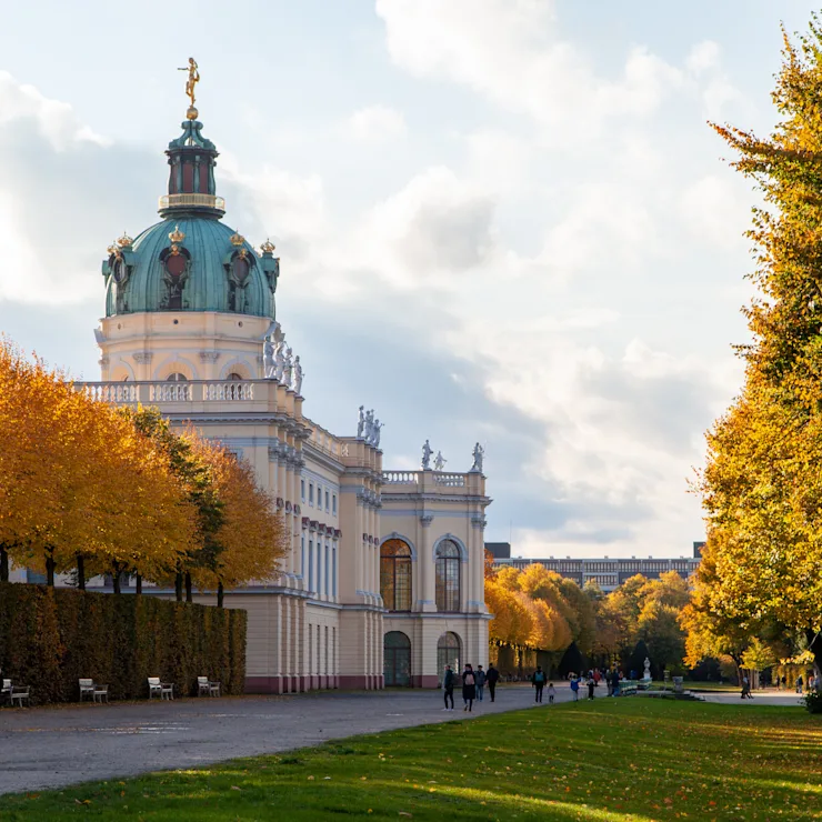 Stadtansicht mit modernen Hochhäusern und einer historischen Kirche im Vordergrund bei Sonnenuntergang.