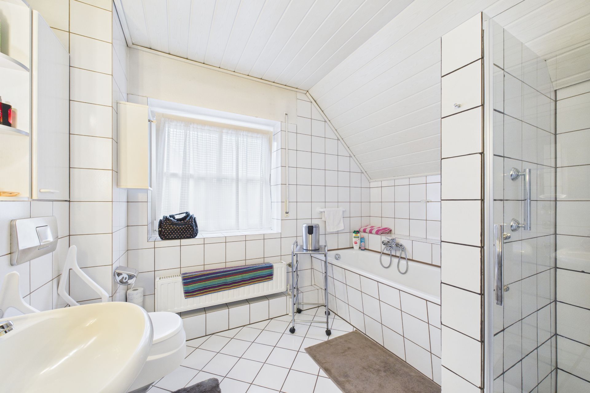 Helles Badezimmer mit Dusche, Badewanne, Waschbecken und Fenster.