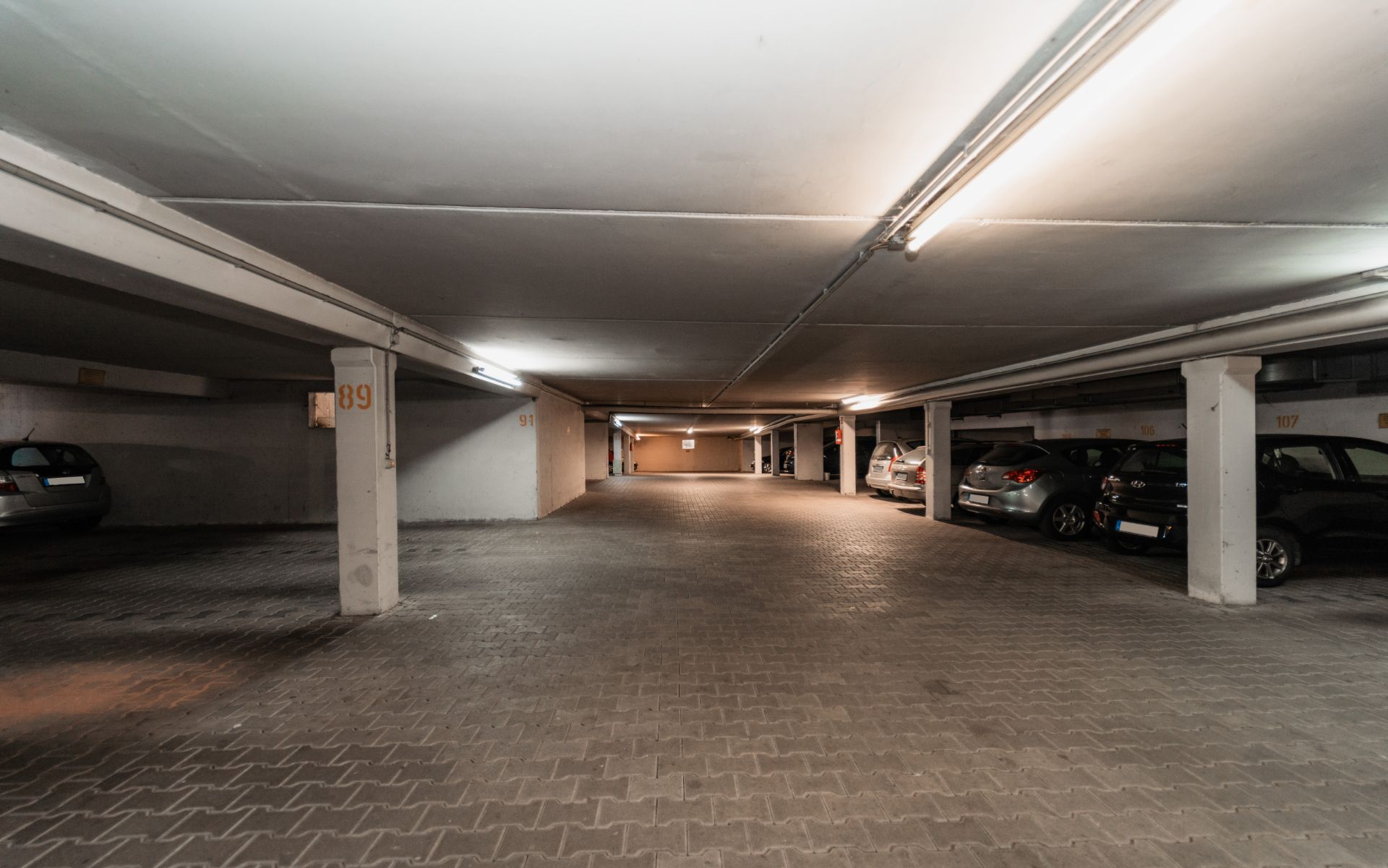 Tiefgarage mit geparkten Autos und beleuchteten Stellplätzen.