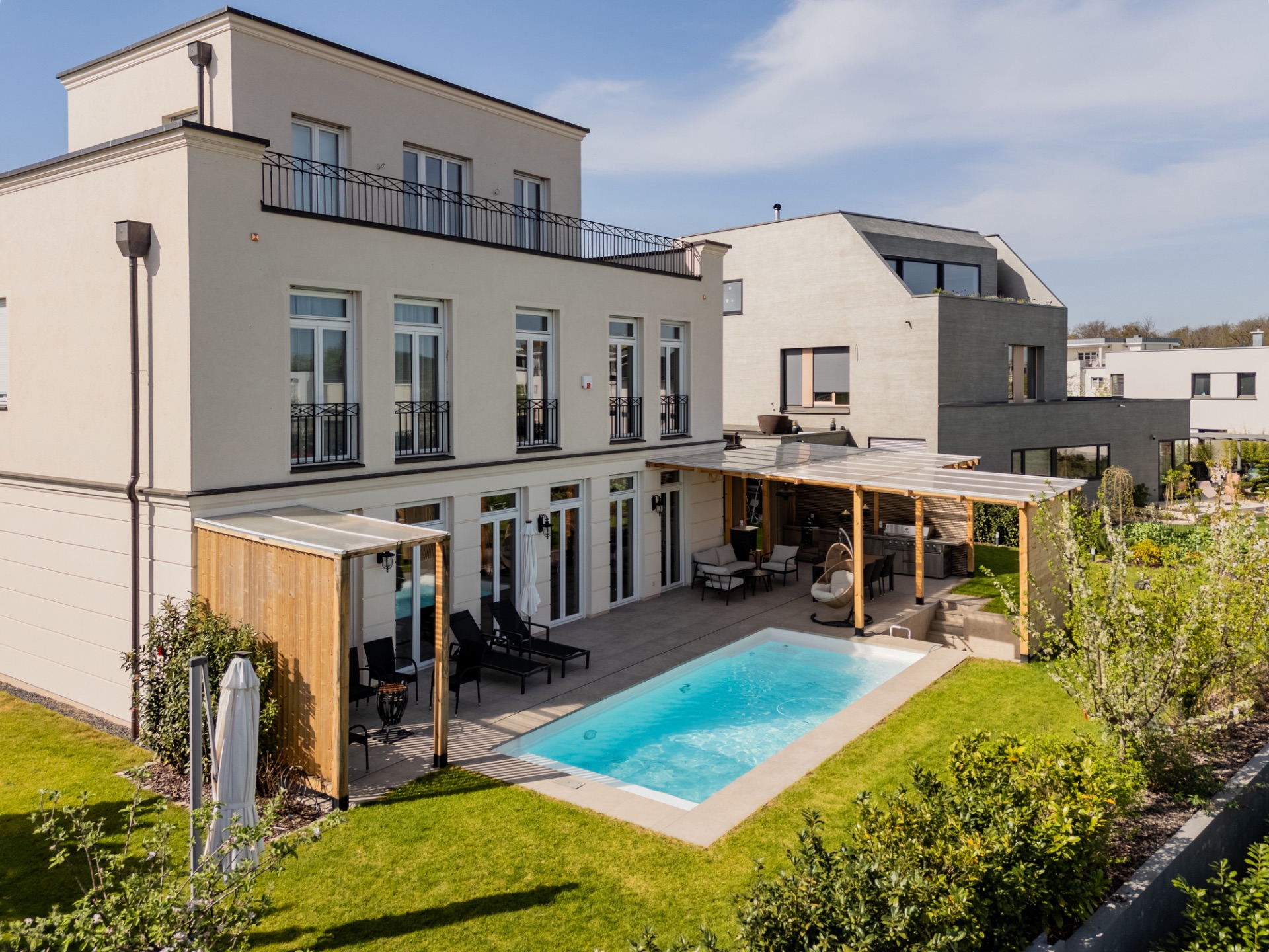 Modernes Haus mit Garten, Terrasse und kleinem Pool im Außenbereich.