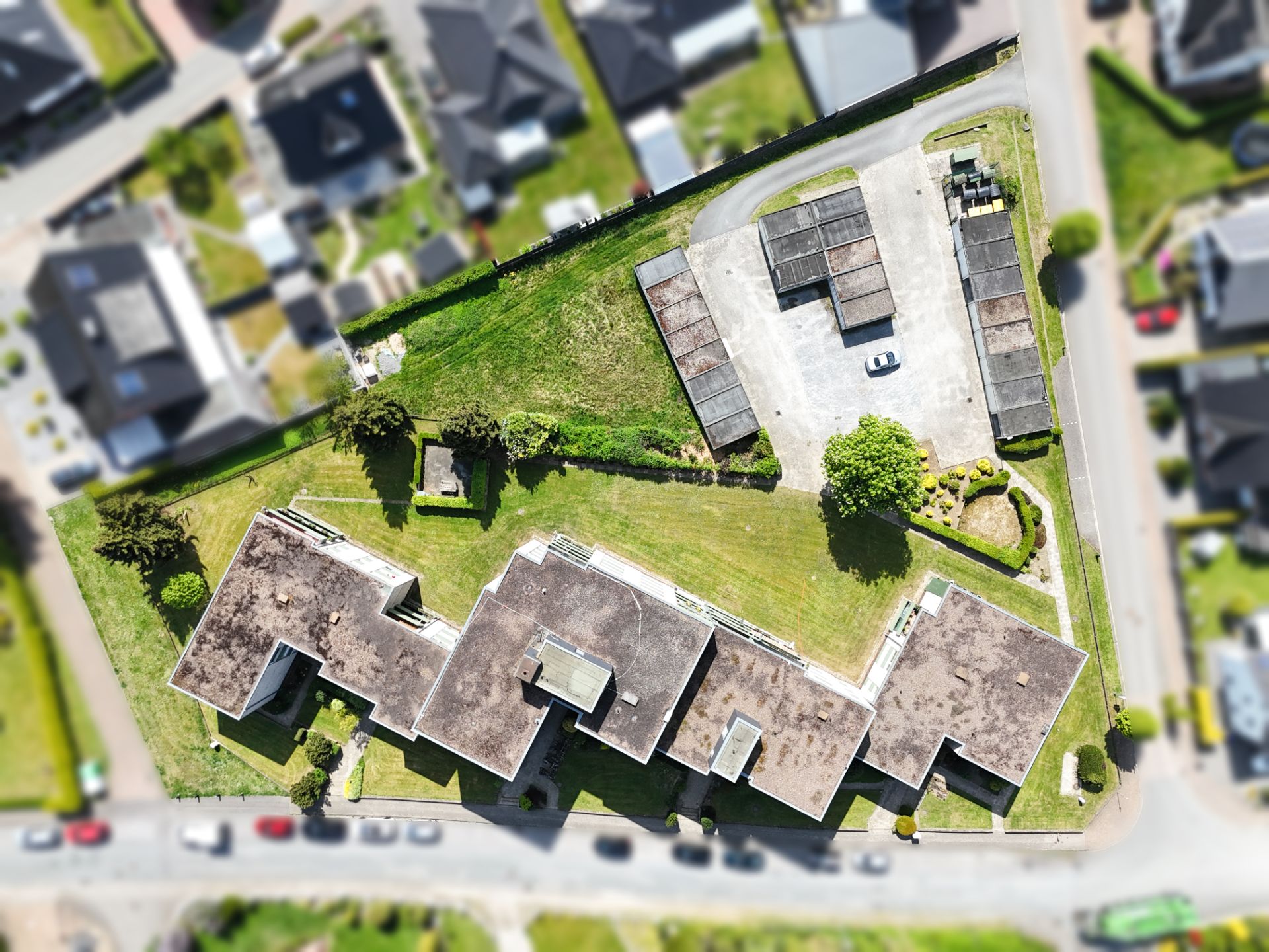 Luftaufnahme eines Wohngebäudes mit großem Garten und Parkplätzen.