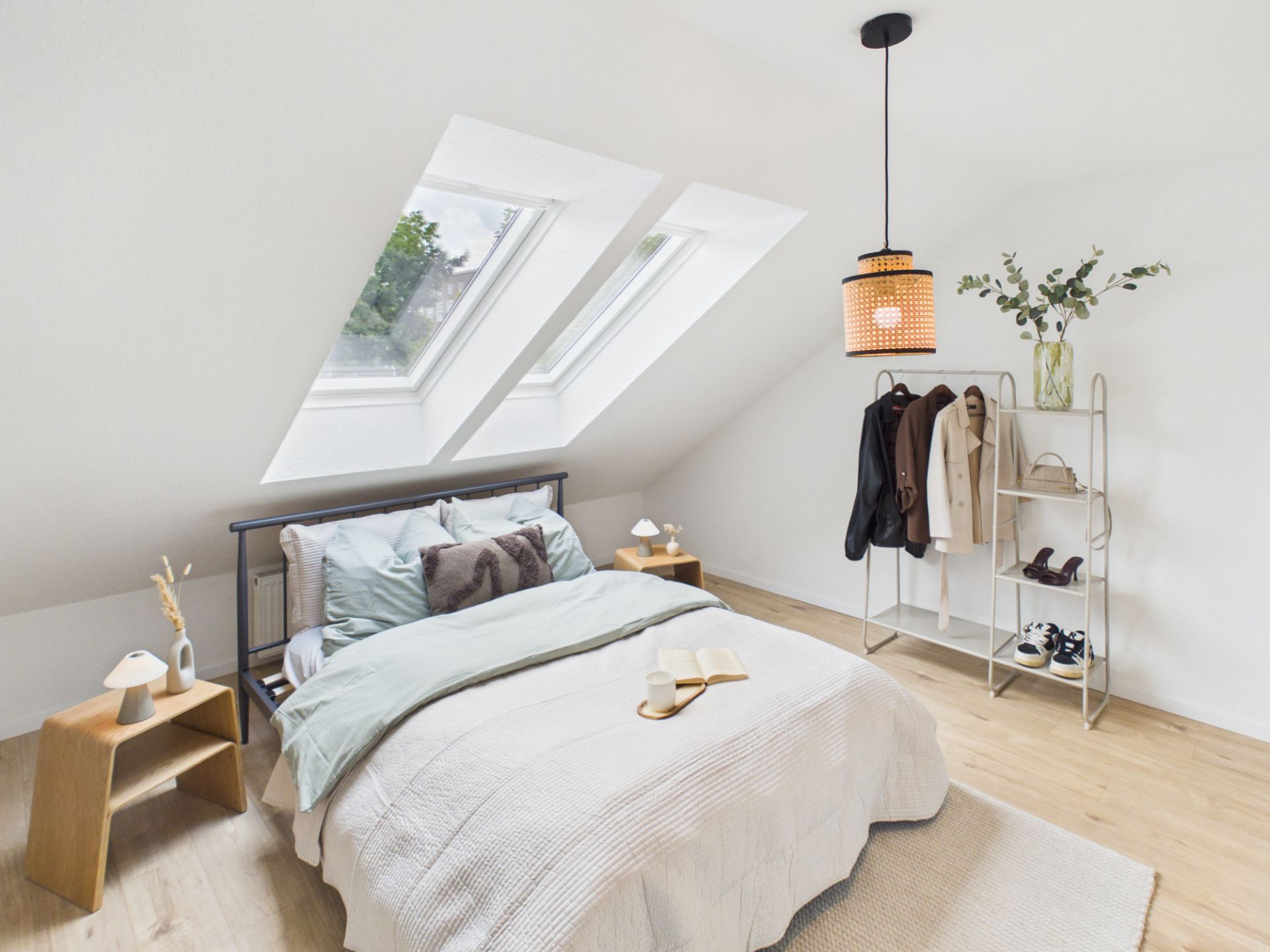 Helles Schlafzimmer im Dachgeschoss mit Bett, Nachttischen, Regal und zwei Dachfenstern.