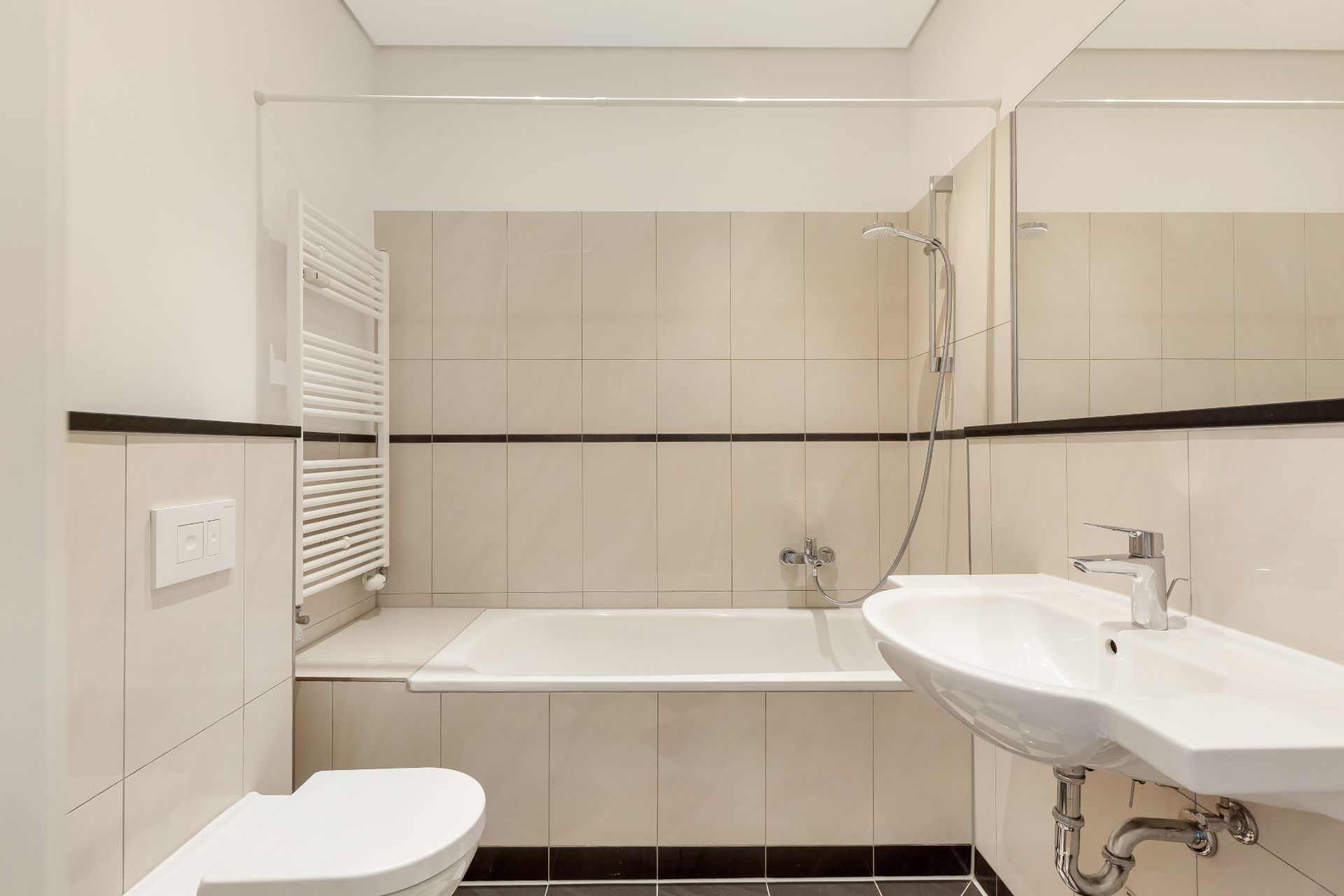 Helles Badezimmer mit Badewanne, Dusche, Waschbecken, WC und Handtuchheizkörper.