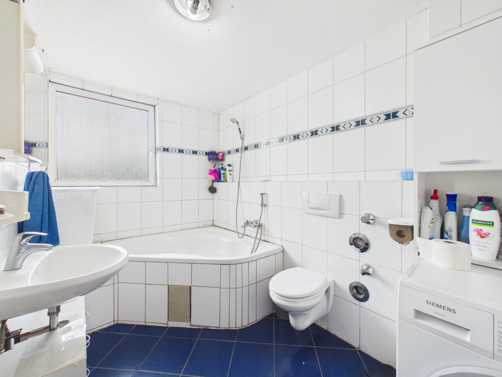 Helles Badezimmer mit Eckbadewanne, Waschbecken, WC und Waschmaschine.