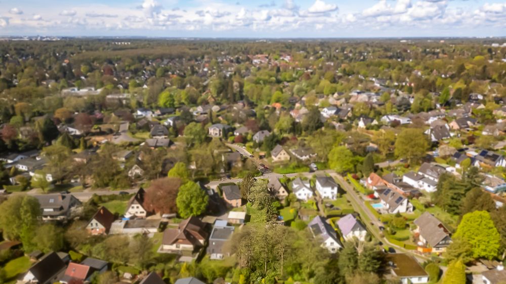 Luftaufnahme eines Wohngebiets mit vielen Häusern, Bäumen und Straßen.