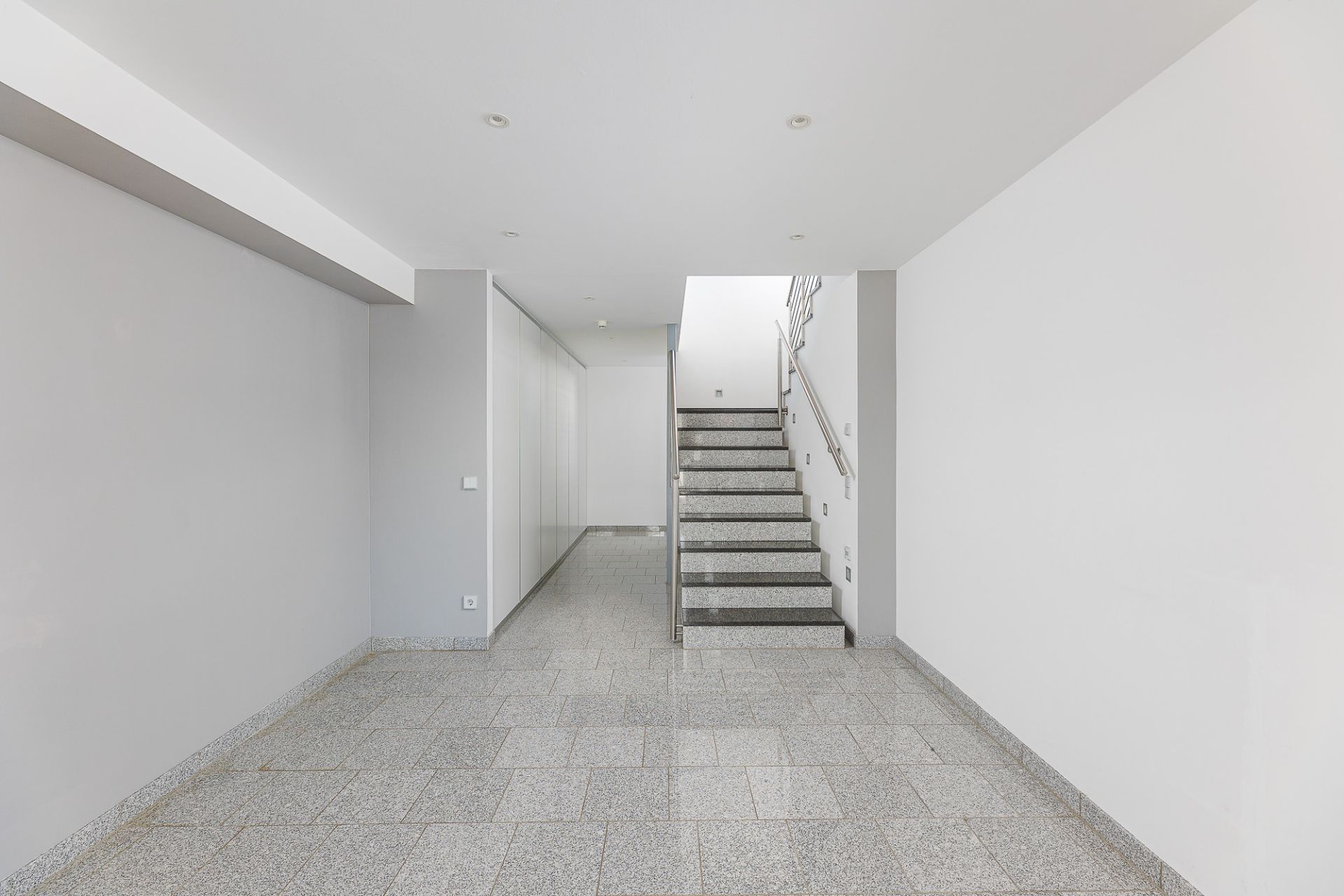 Heller Flur mit grauem Fliesenboden und Treppe nach oben.