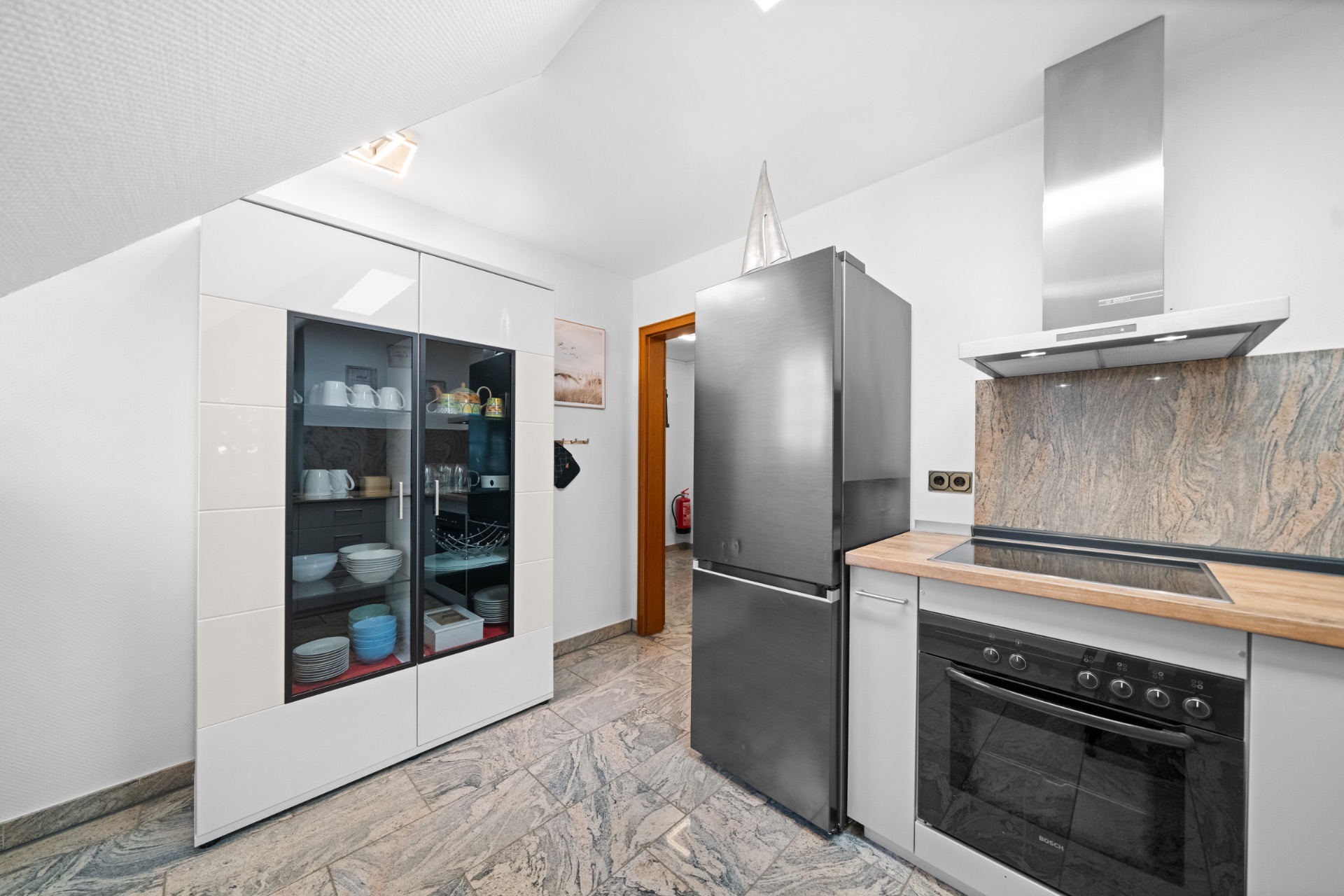 Moderne Küche mit Herd, Kühlschrank und Glasschrank mit Geschirr.